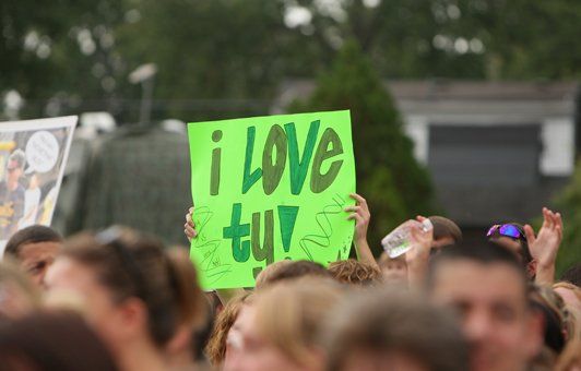 Person in a crowd holding a bright green sign that says 