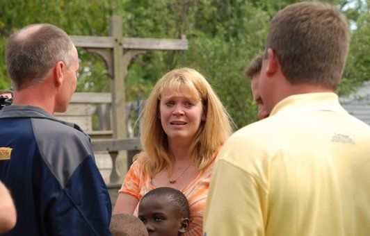 Woman crying, surrounded by people outside.