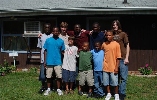 Group of people smiling outside a house.