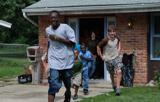 Group of people running out of a brick building with an open door.