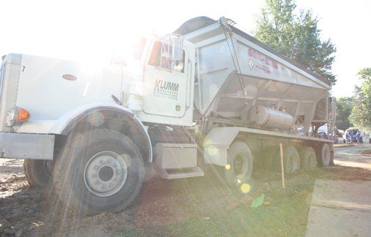 White dump truck parked on a construction site; bright sunlight.