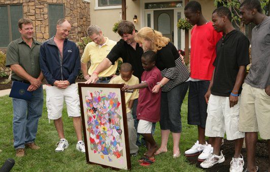 Group of people looking at a colorful painting outdoors in front of a house.