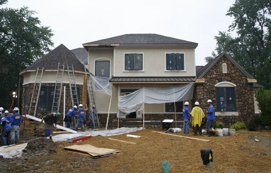 Construction workers at a two-story house under renovation, with scaffolding, 