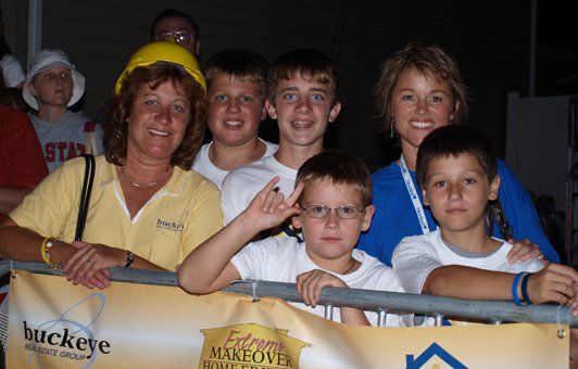Group of people, smiling, behind a barrier with an 