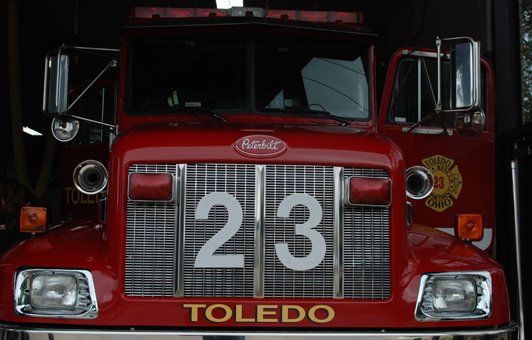 Red Toledo fire truck, number 23, parked in a bay, with doors open, ready to respond.