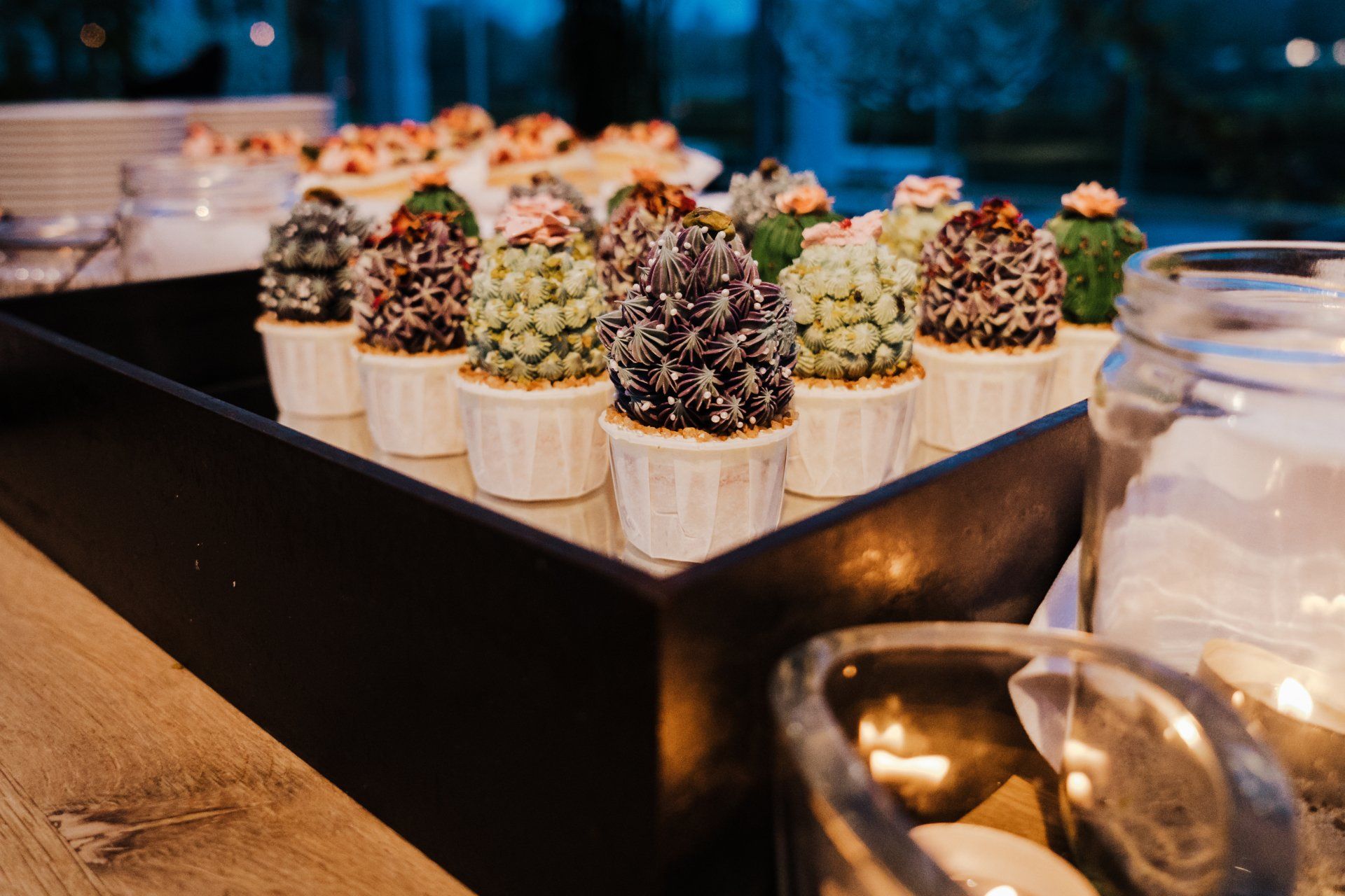 Een schaal met cupcakes in de vorm van een cactus op een tafel.