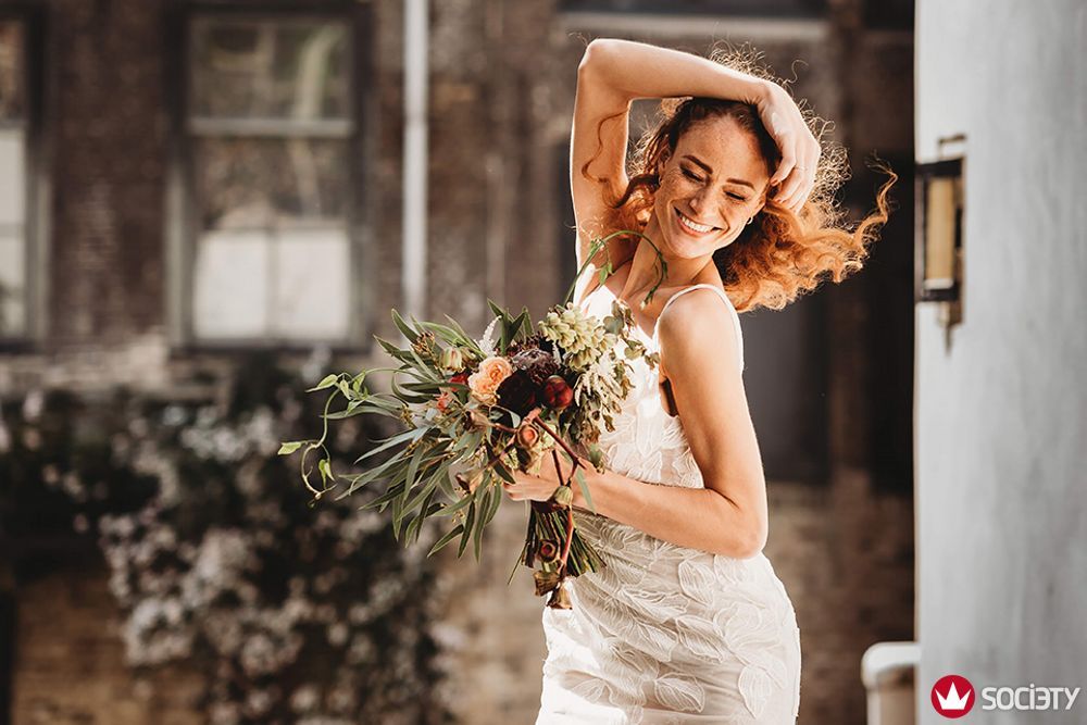 Een vrouw in een trouwjurk houdt een boeket bloemen vast.