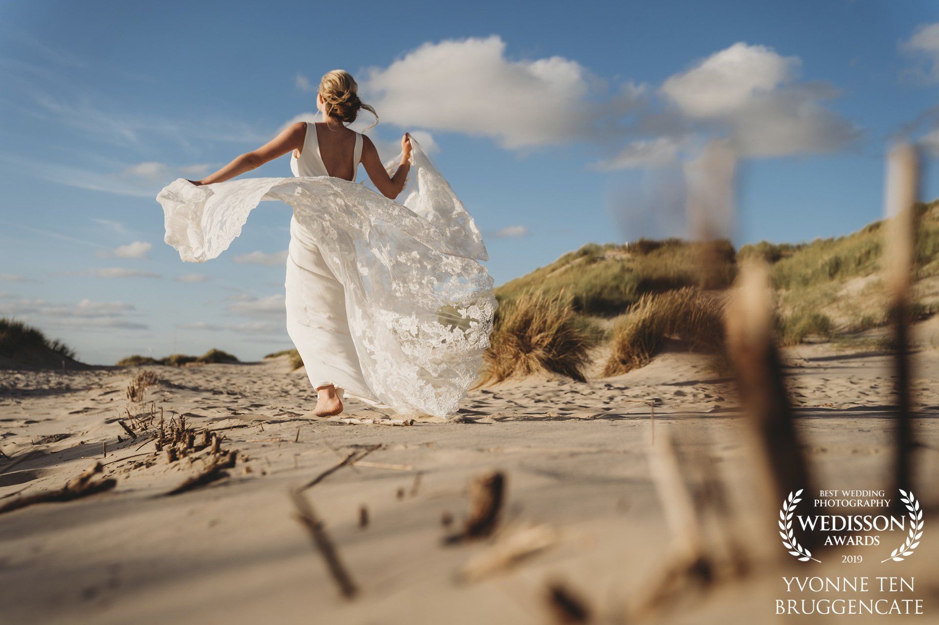 Een vrouw in een witte jurk rent op het strand.