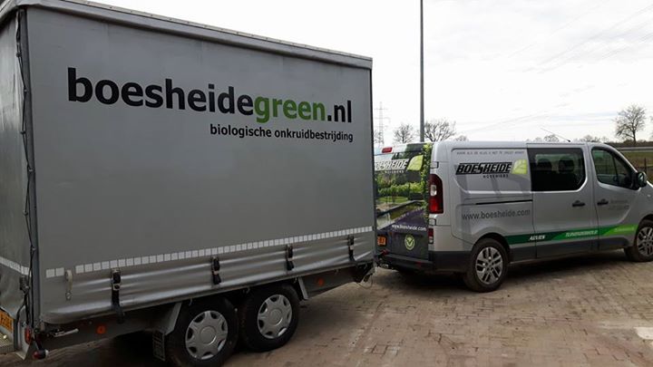 Grijze bestelbus en aanhanger met het logo 