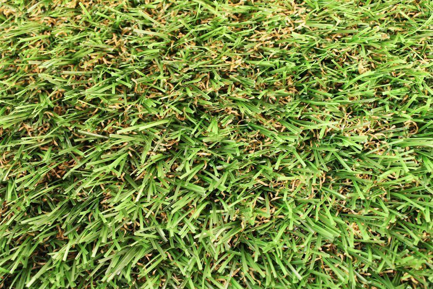 Close-up van groen kunstgras met hier en daar wat bruine slierten.