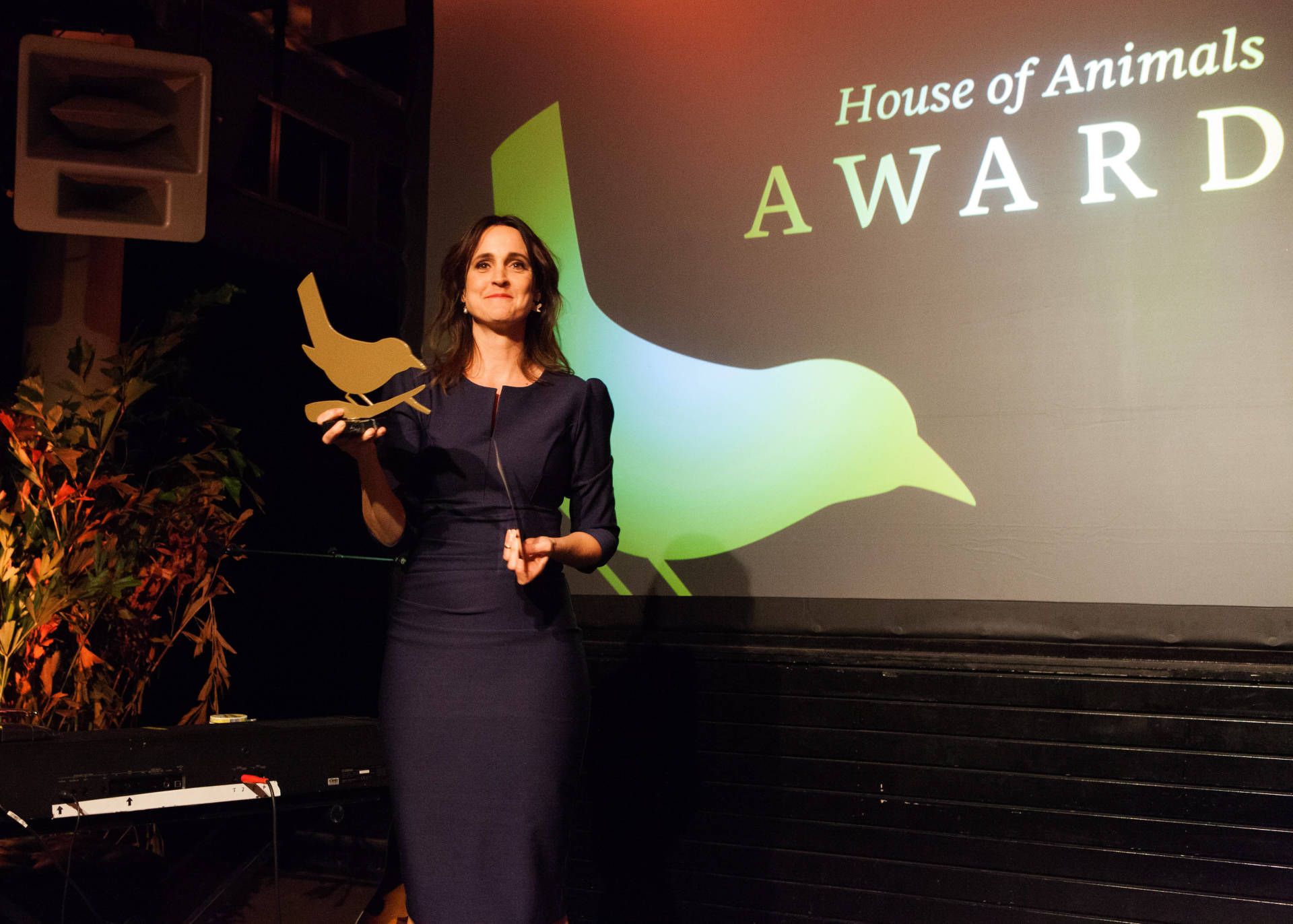 Een vrouw houdt een prijs vast voor een scherm met de tekst house of animals award