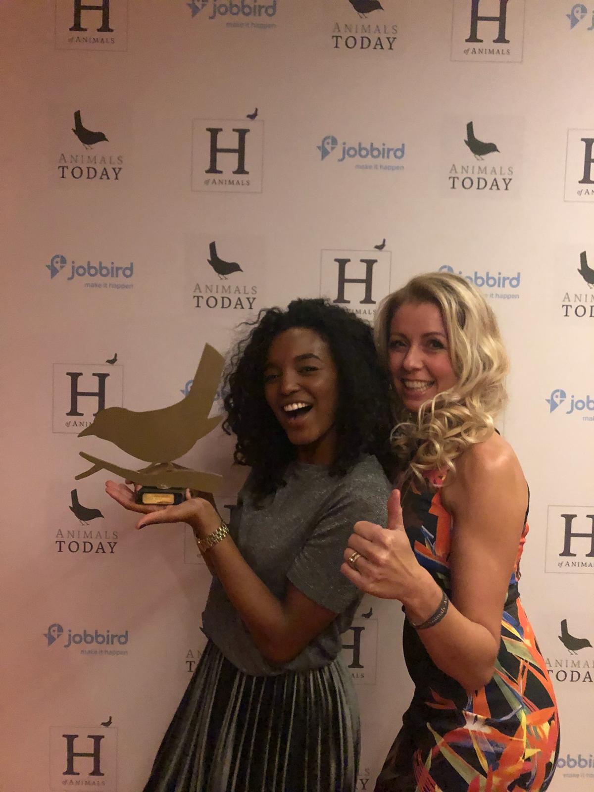Twee vrouwen poseren voor een foto en één van hen houdt een trofee vast.