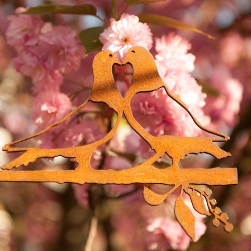 Een paar vogels zittend op een tak met bloemen op de achtergrond