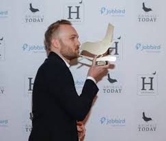 Een man in pak houdt een trofee vast en kust deze.