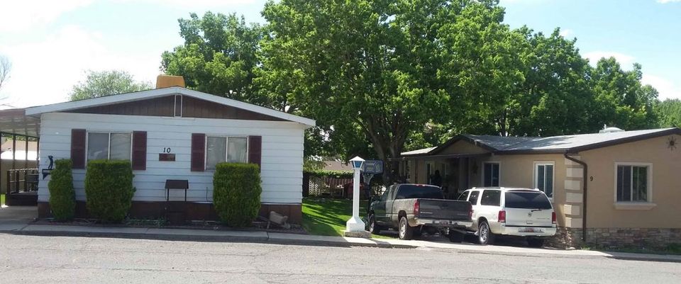 Front of a mobile home with trucks in the driveway at South Springville Mobile Home Park