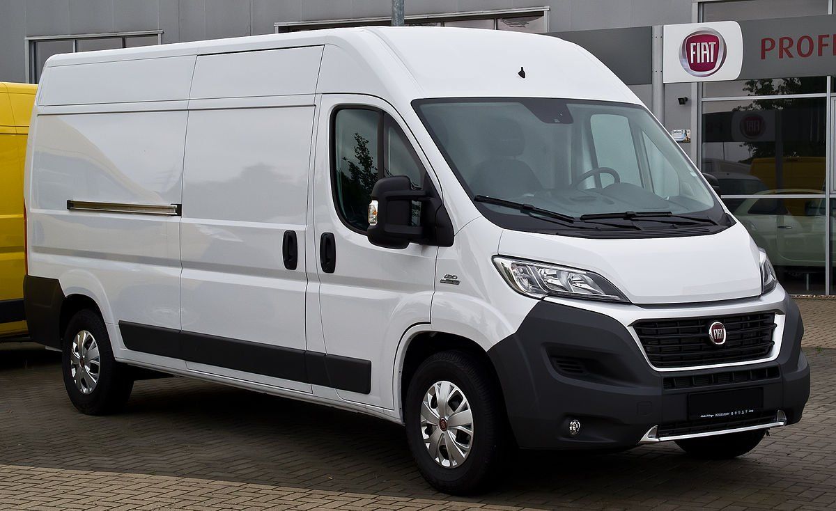 A white van is parked in front of a building.