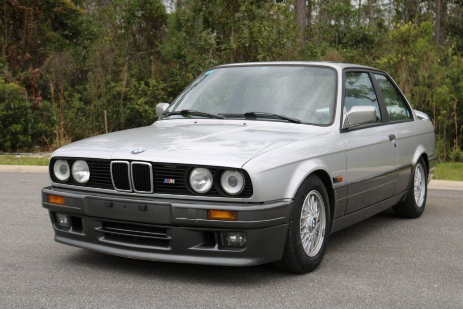 A silver bmw is parked on the side of the road.