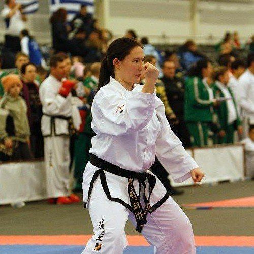 Miss Natalie as a Junior competing at the European Championships Four martial artists stood next to a banner
