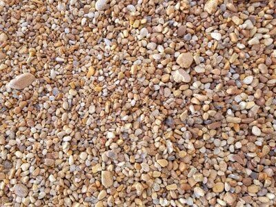 Close-up of a sandy gravel surface with small tan, brown, and white pebbles