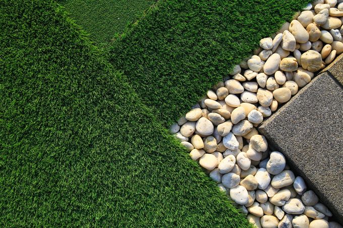 Green grass beside a curved border of white pebbles and gray pavement