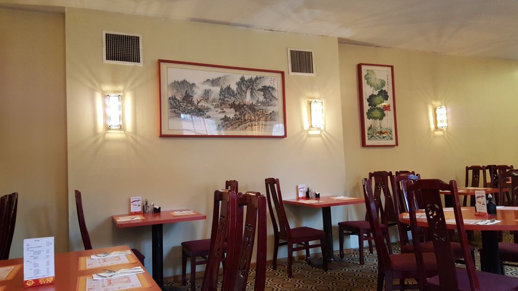 A restaurant with tables and chairs and a painting on the wall.