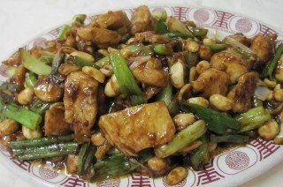 Czechuan Chicken with peanuts, scallions, and sauce on a patterned plate.