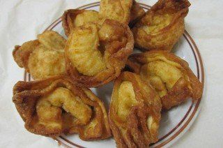 Fried, golden-brown wontons arranged on a white plate with a brown border.