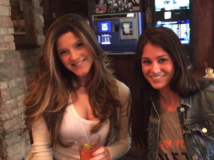 Two women are posing for a picture and one is wearing a shirt that says new york