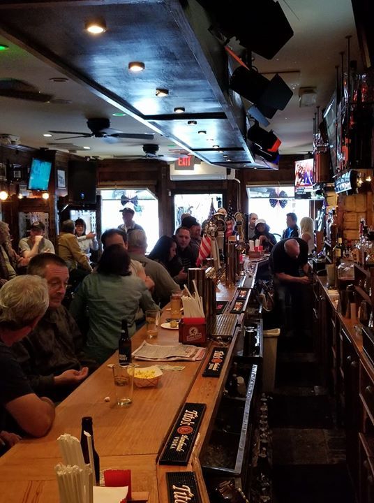 A group of people are sitting at a bar in a restaurant