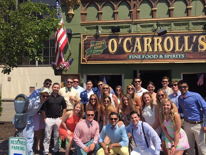 A group of people posing in front of o carroll 's fine food & spirits