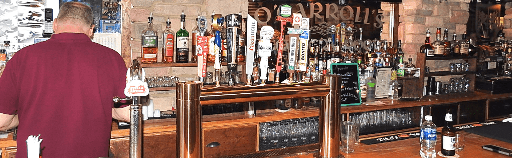 A man in a red shirt is standing at a bar