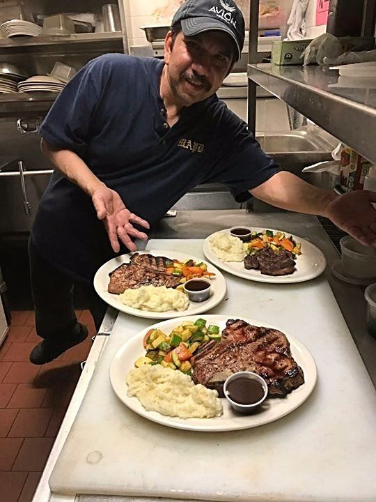 A man is standing in front of two plates of food in a kitchen.