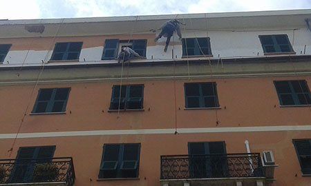 un uomo con un imbracatura appeso a delle corde sulla facciata di una casa