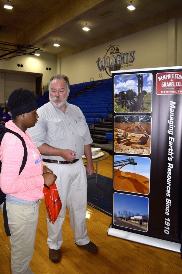 Man and student at a display. Display shows photos of earth resources with text 