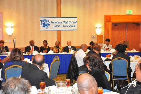 Hamilton High School alumni gathering at a formal banquet. People seated at tables, a banner displayed.