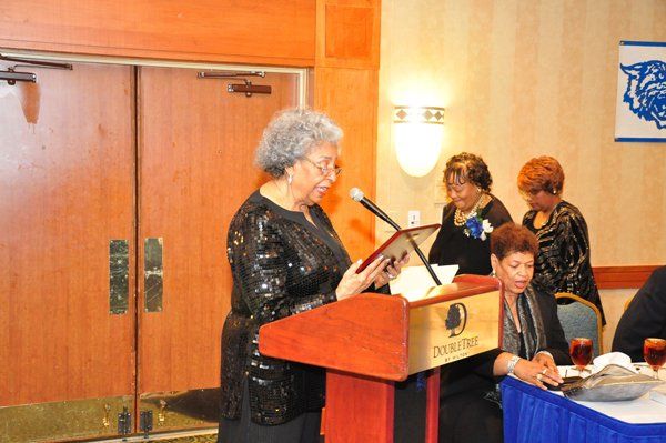 Woman speaking at podium, other women in the background. Event at Doubletree hotel.