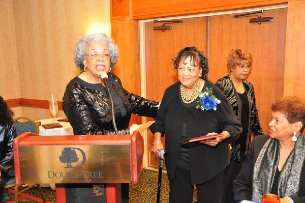 Woman speaking at a podium, handing a woman a plaque at a DoubleTree event.
