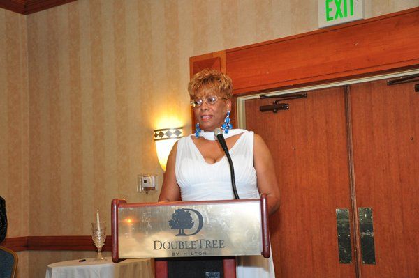 Woman speaking at a DoubleTree podium in a room with a decorative backdrop.