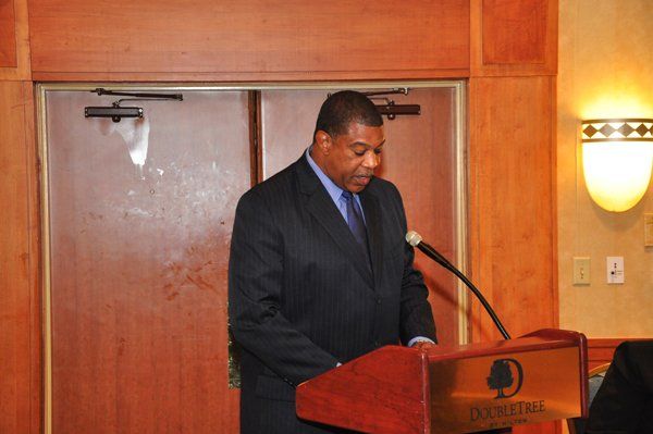 Man in suit speaking at a podium with a DoubleTree logo.