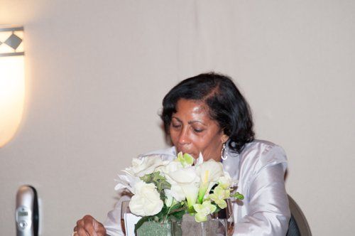 Woman smelling a bouquet of white flowers, light skin, dressed in white, indoor setting.
