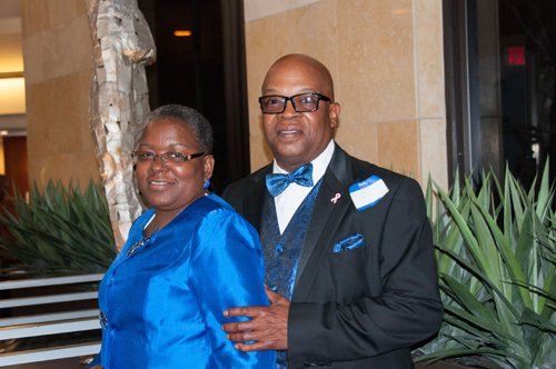 Couple in formal attire; woman in blue, man in a suit with bow tie, smiling.