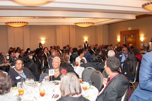 People seated at tables in a banquet hall, attending an event.