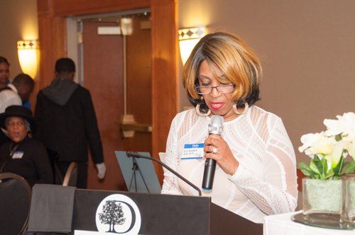 Woman speaking at a lectern with a microphone in front of a group.