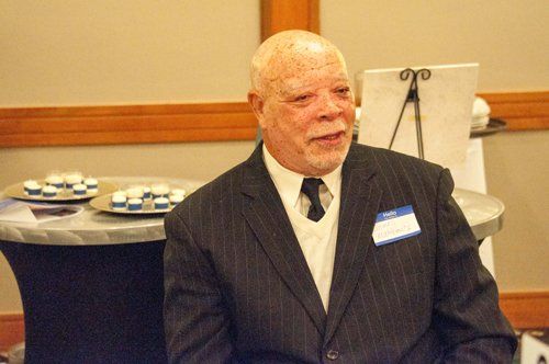 Man in suit, smiling, indoors at an event.