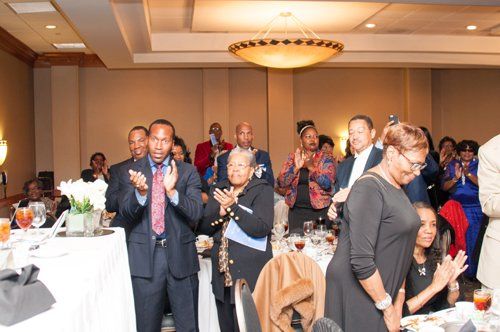 People applauding at a formal event in a banquet hall.