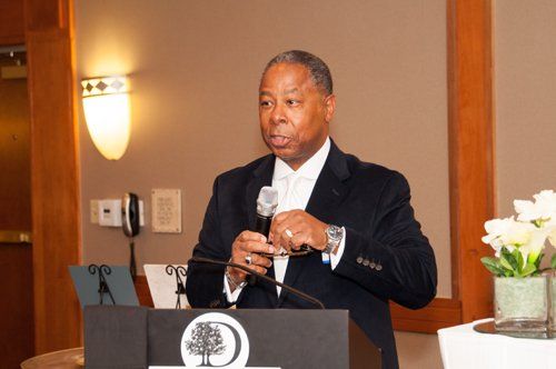 Man in suit speaking at podium with microphone, indoors.