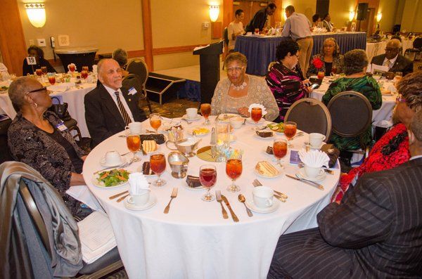 People seated at a round table, enjoying a meal at an event in a banquet hall.