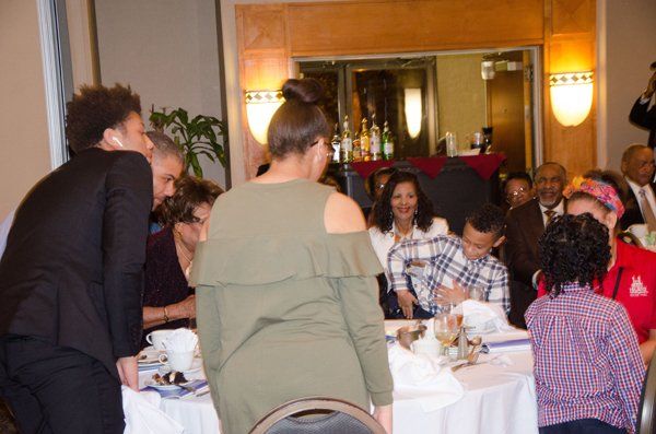 People gathered at a table in a formal setting, several are turned towards the camera.