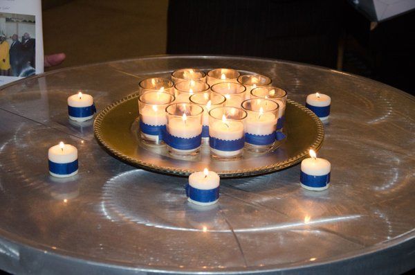 Lit candles on a metal table, some arranged in a circle on a silver platter with blue ribbon.