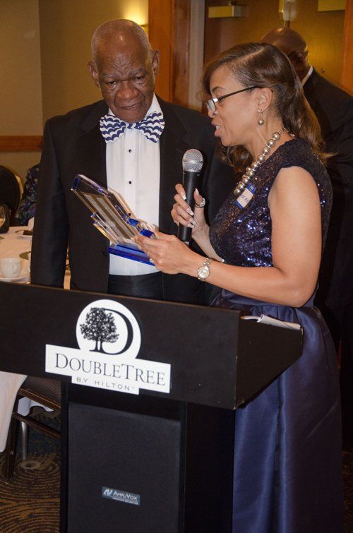 Woman presenting an award to a man at a DoubleTree by Hilton event.